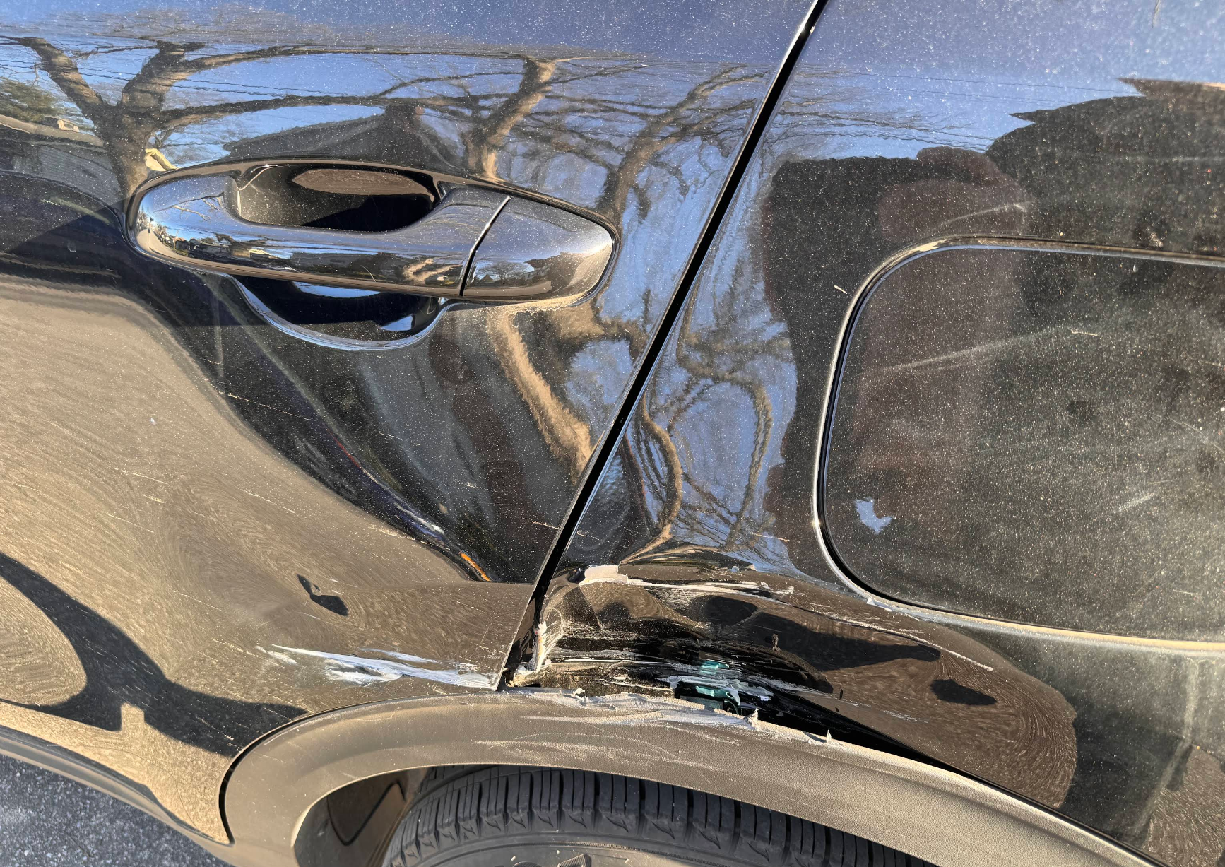 Door and quarter panel collision damage on a black vehicle
