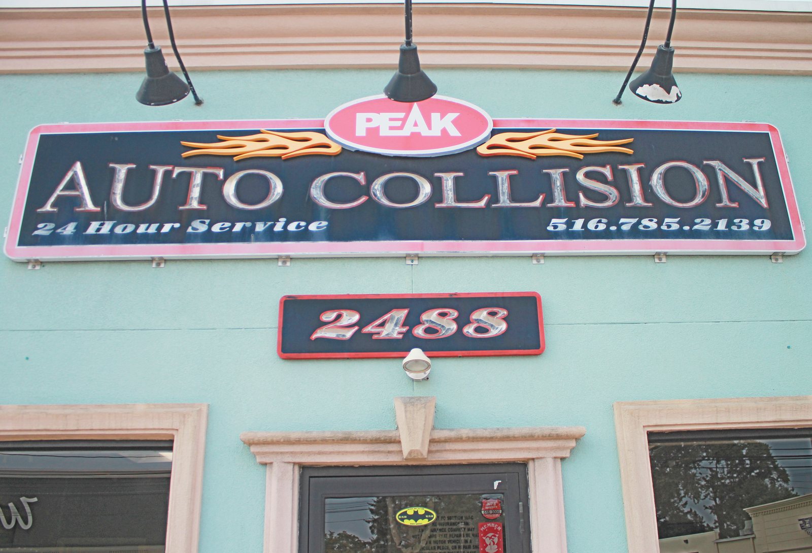 Peak Auto Collision sign above the shop entrance at 2488 Merrick Road