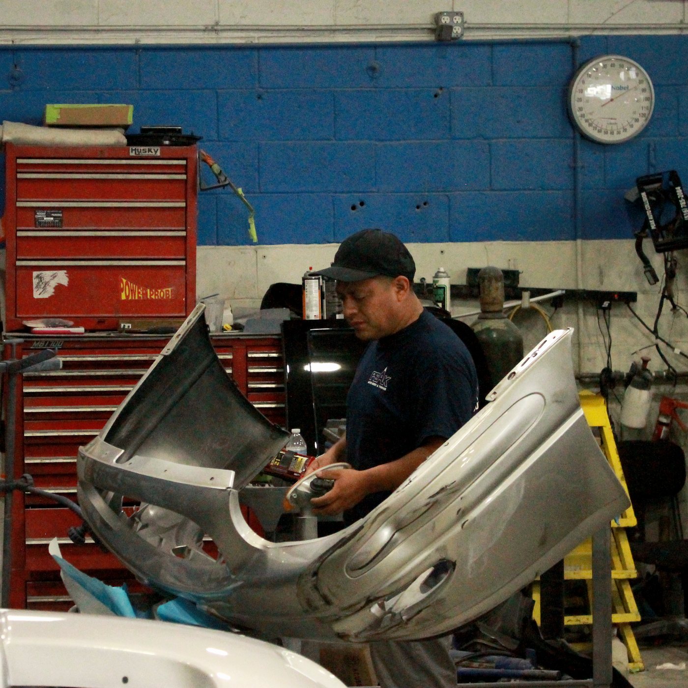 Peak Auto Collision technician prepping a silver fender and bumper cover